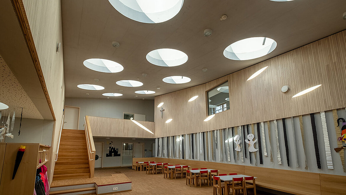 Multi-purpose room of the kindergarten St. Severin in Garching with round flat roof windows Light play of the round glass skylights in the lounge of a kindergarten | insights by LAMILUX