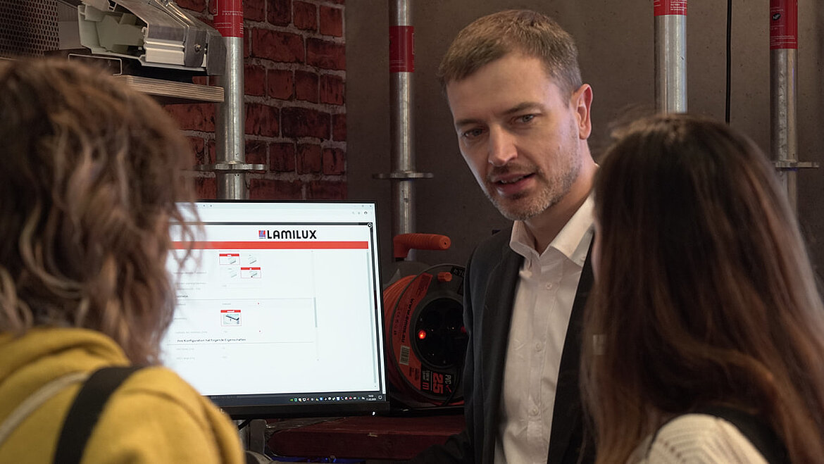 Construction engineer Carsten Ficker explains LAMILUX product configurator Carsten Ficker Head of LAMILUX Academy at digitalBAU with two exhibition visitors | insights by LAMILUX