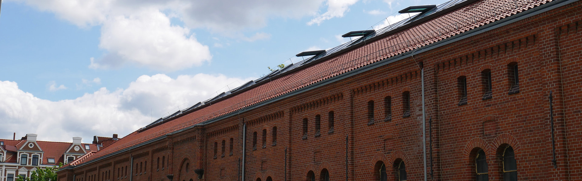 Red tiled roof with numerous solar panels on historic brick building.