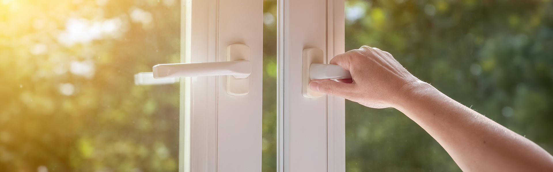 A hand opens a white plastic window using a handle
