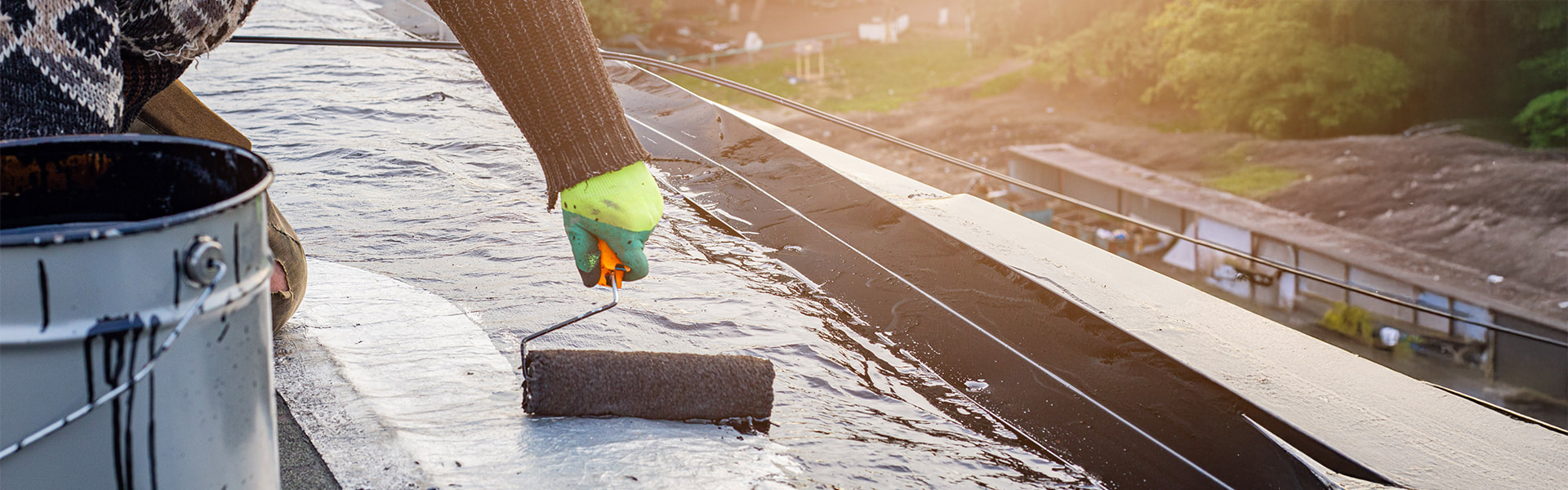 Roofers waterproofing a flat roof with liquid plastic