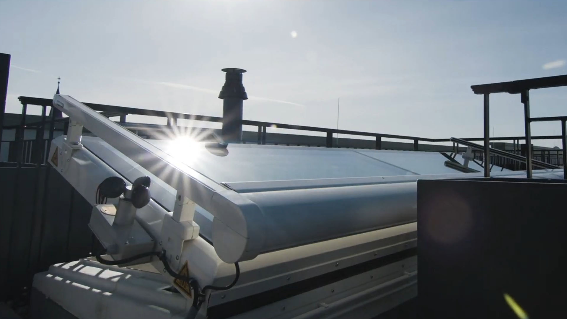 Open LAMILUX flat roof access with sunlight reflection on the glass surface.
