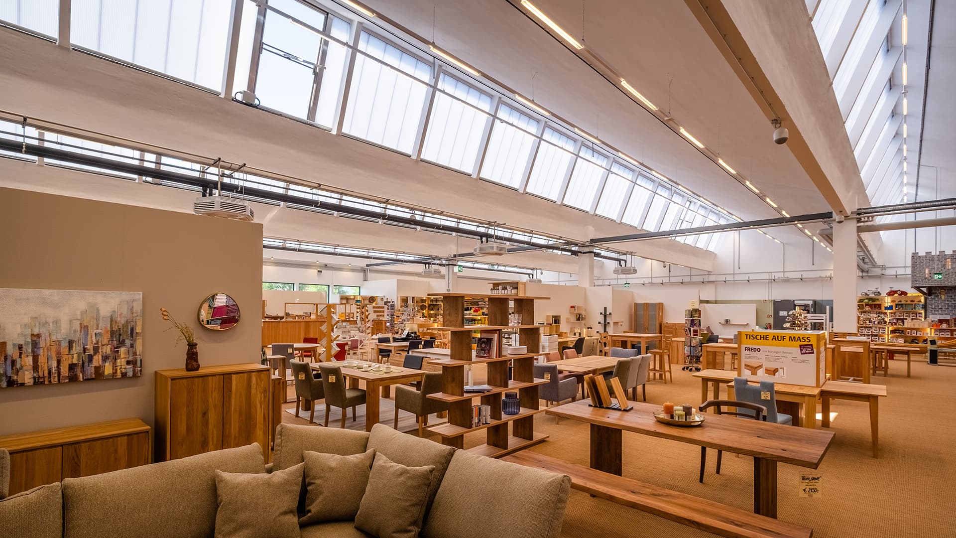 Interior view of the old post station in Leipzig, repurposed as a furniture store with modern design, natural skylights, and stylish furniture.