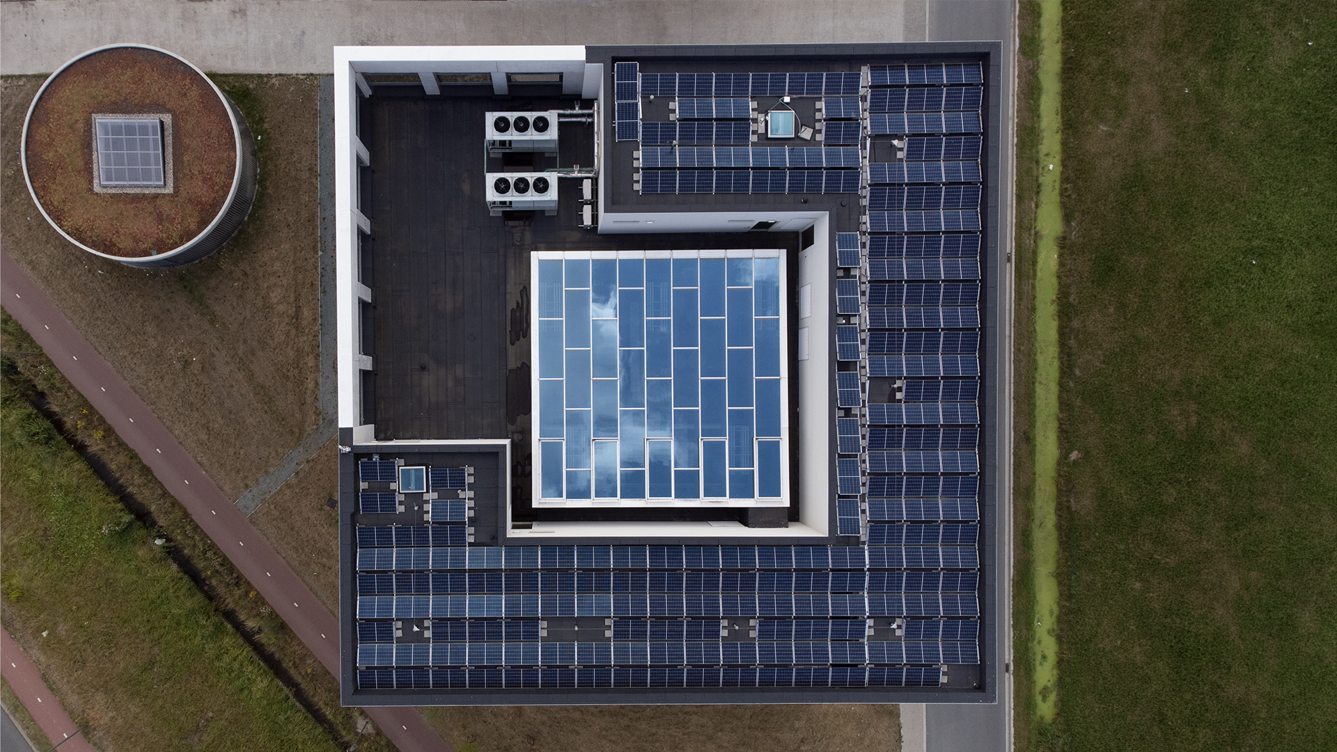 Aerial view of a flat roof with central glass roof and surrounding solar panels