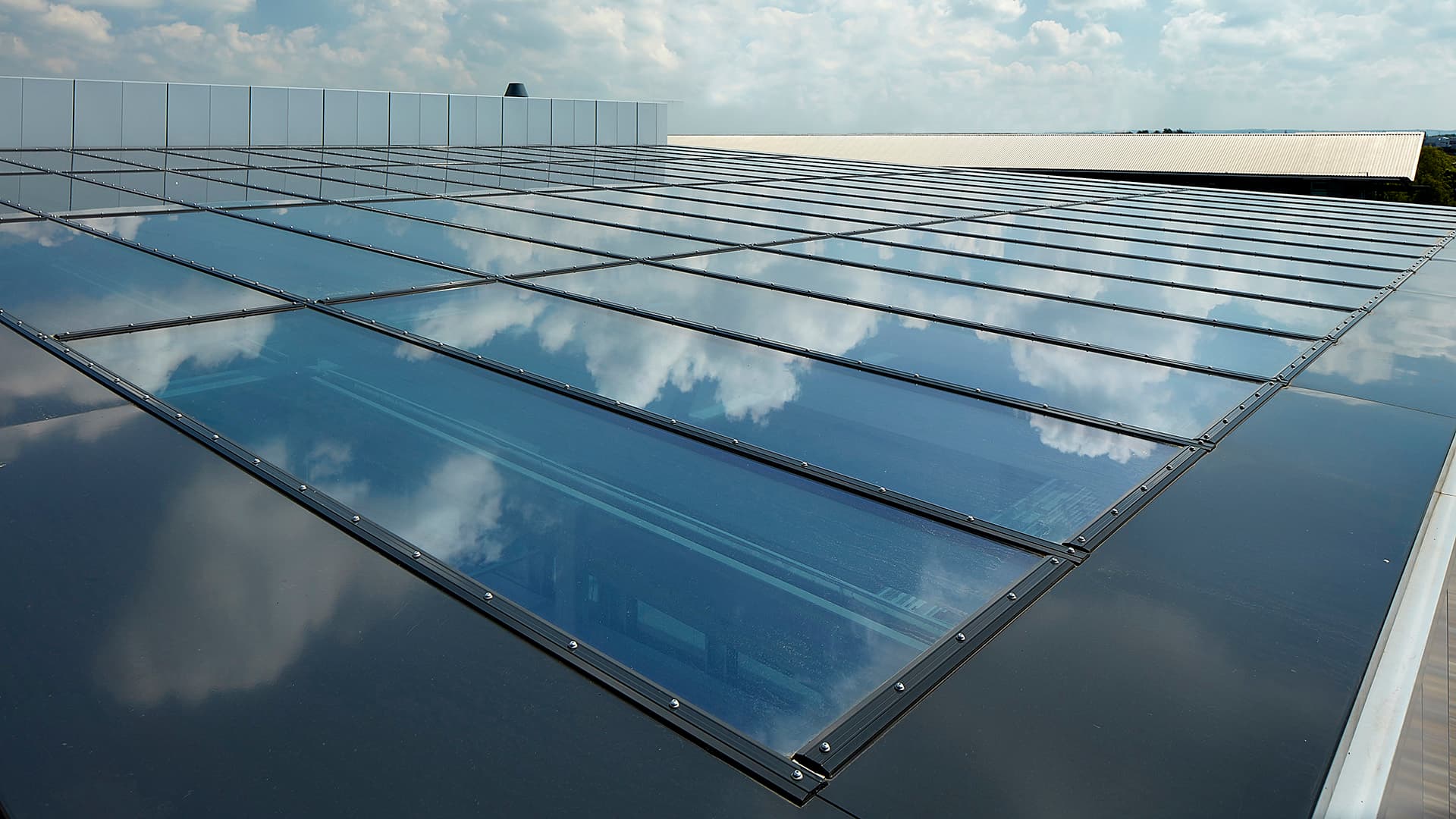 Glass roof of the commercial building in Milton Park, England, reflecting the sky and clouds on its surface.