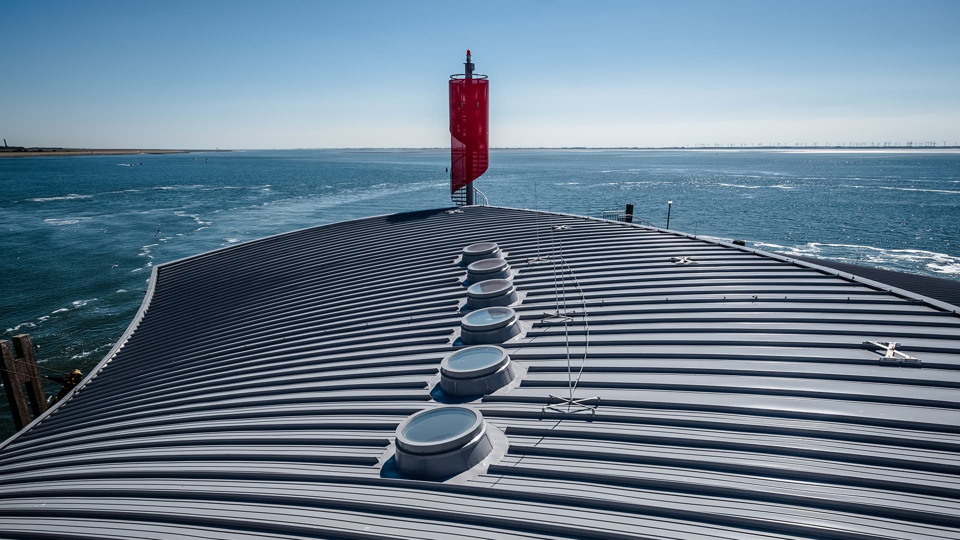 Roof of the Norderney ferry terminal featuring round skylights for natural daylight, with the sea.